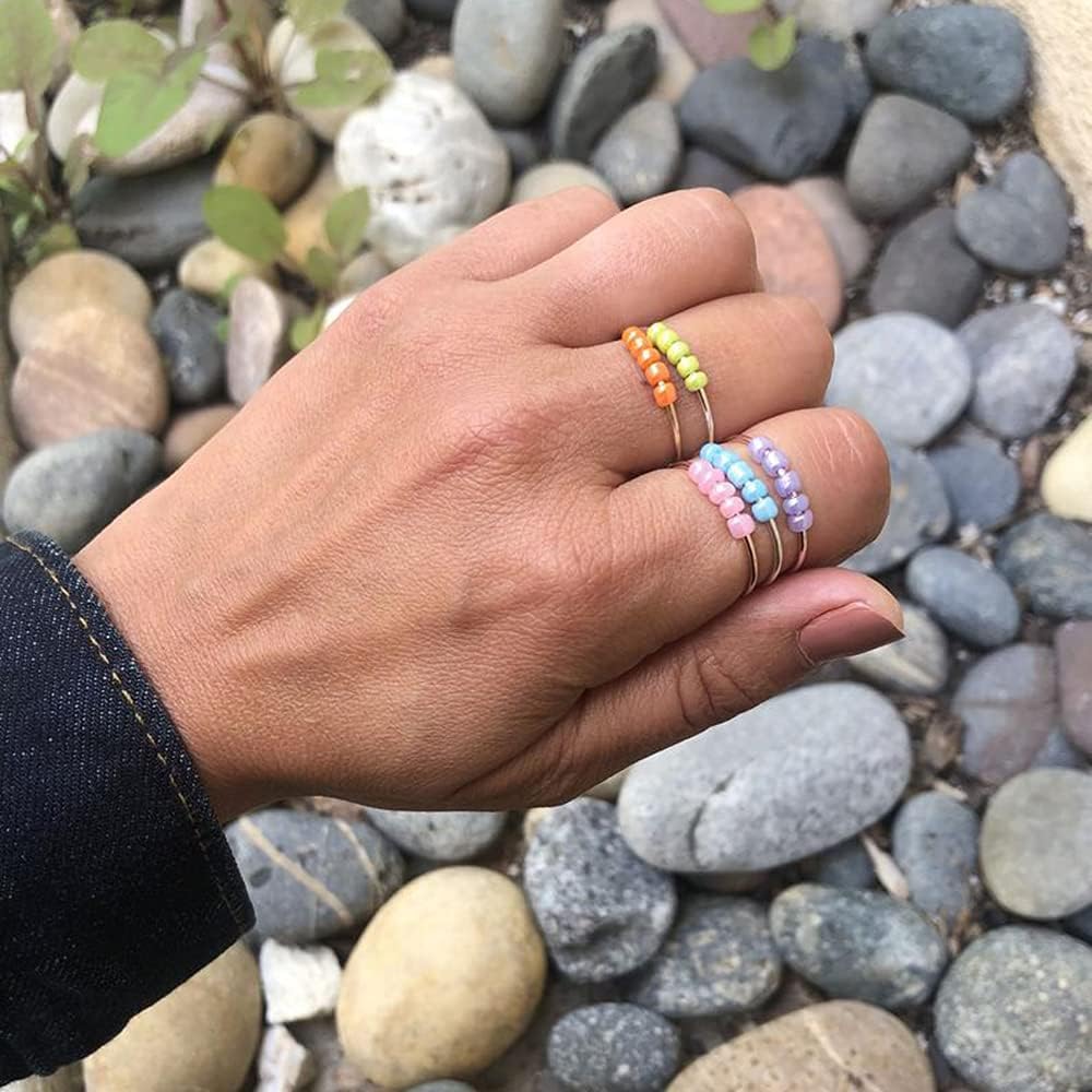 Stack of multiple OIDIMS boho spinner rings showcasing vibrant color variations.