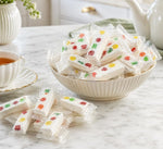 Assortment of individually wrapped DM Sweets chewy nougats spread across a clean background.