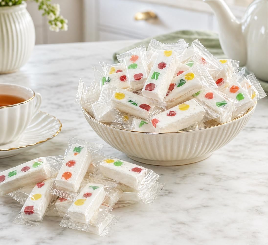 Assortment of individually wrapped DM Sweets chewy nougats spread across a clean background.