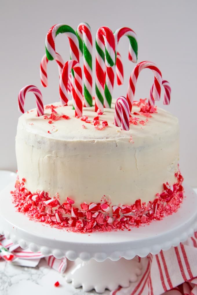 Individually wrapped red peppermint yellow rainbow cherry and green mint candy canes arrayed flat.