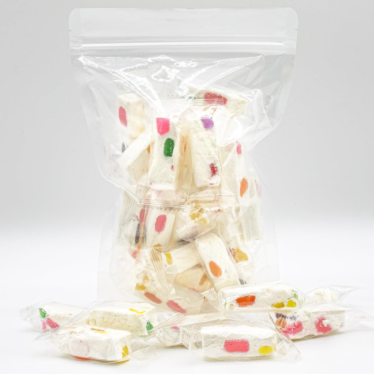 Clear plastic wrapped individual pieces of tropical fruit flavored white nougat ready for party hosting.