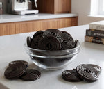 A single DM Sweets Black Licorice Wheel partially unrolled to display the long playful strand structure.