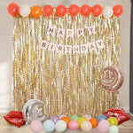 Trimming the length of a gold tinsel curtain with scissors for custom wall fit