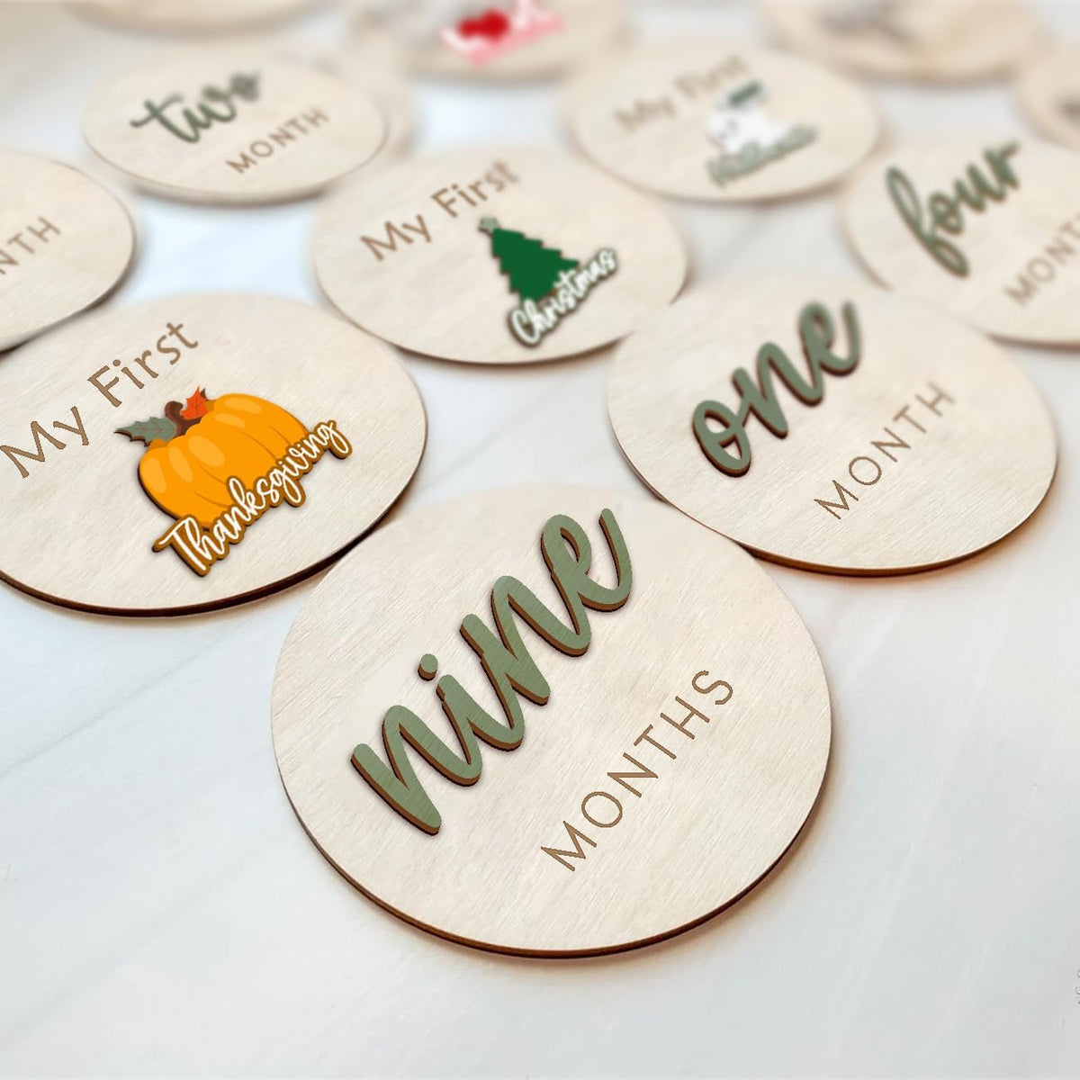 Cephira monthly baby milestone maker discs set in sage green front view displaying three dimensional lettering