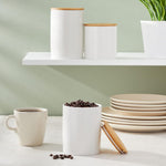 White ceramic food storage jars with bamboo lids on countertop