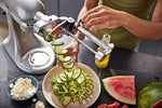KitchenAid spiralizer attachment connected to a stand mixer slicing a vegetable