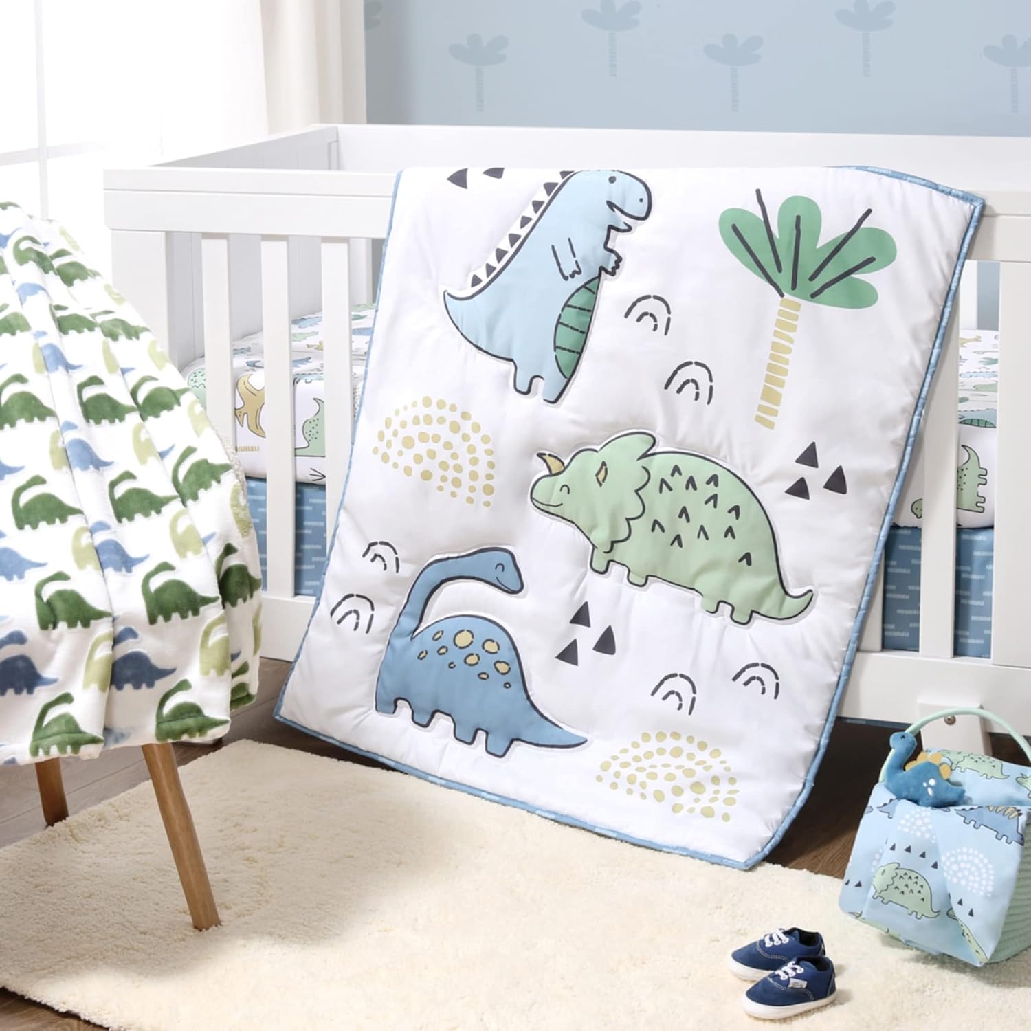 The Peanutshell 5 Piece Baby Crib Bedding Set front view featuring blue dino quilt on standard mattress