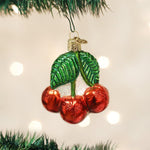 Close up of hand painted glossy red cherries glass ornament with green glitter leaves