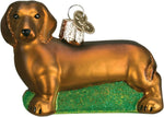 Old World Christmas Chihuahua ornament resting on its sparkling green glitter base.