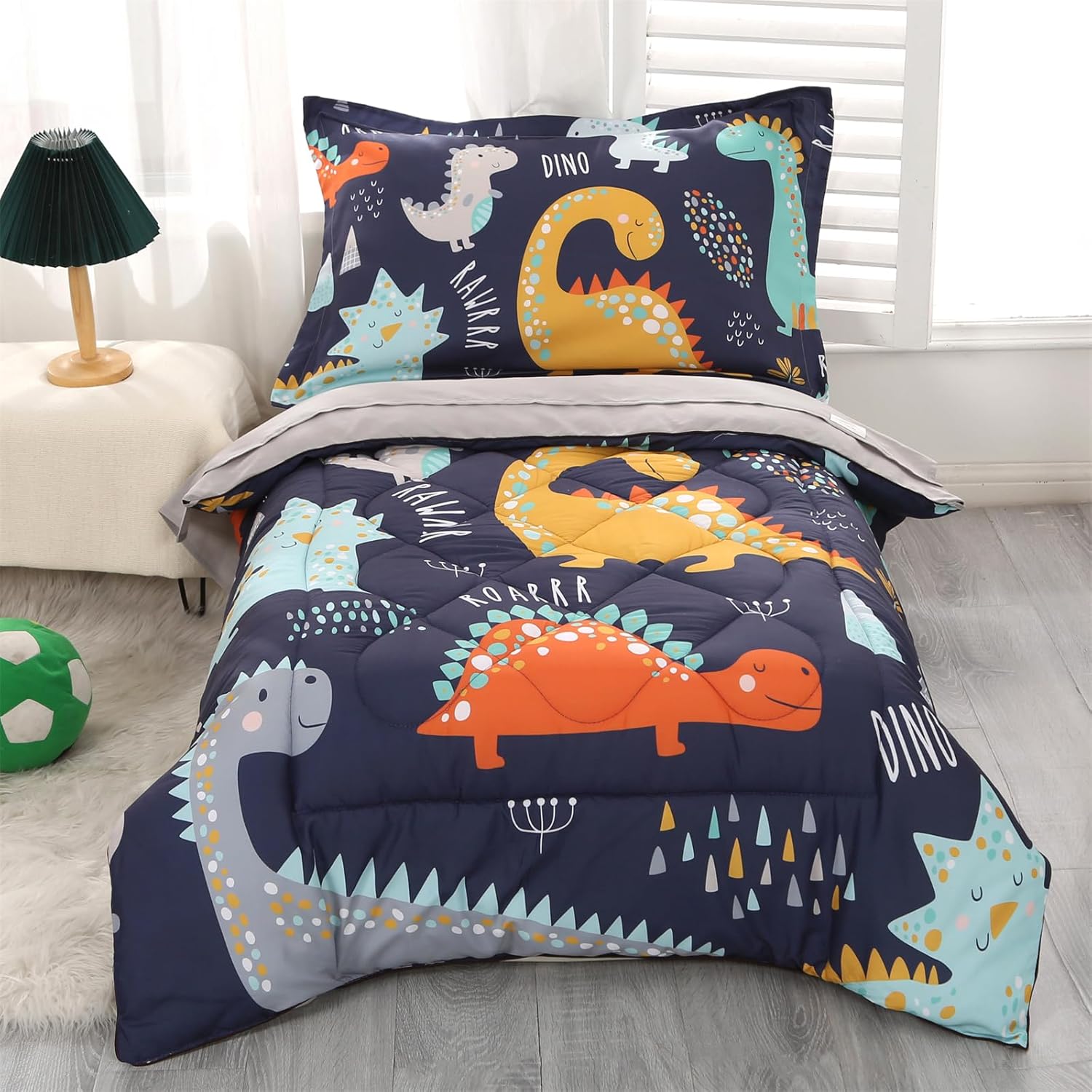 Wowelife Dinosaur Toddler Bedding Set front view featuring dark blue comforter with colorful cartoon dinosaurs on a toddler bed.