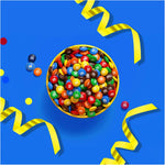 Close up of a single blue portable M&M's Minis dispenser with vibrant colorful candy shells spilling out