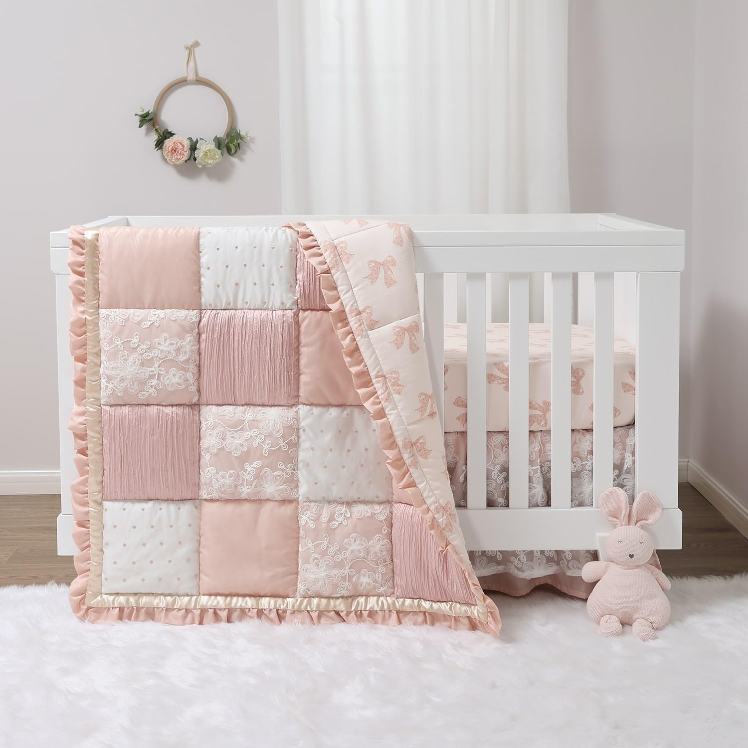 The Peanutshell Grace baby crib bedding set front view showcasing the pink and gold patchwork comforter inside a white wooden crib.