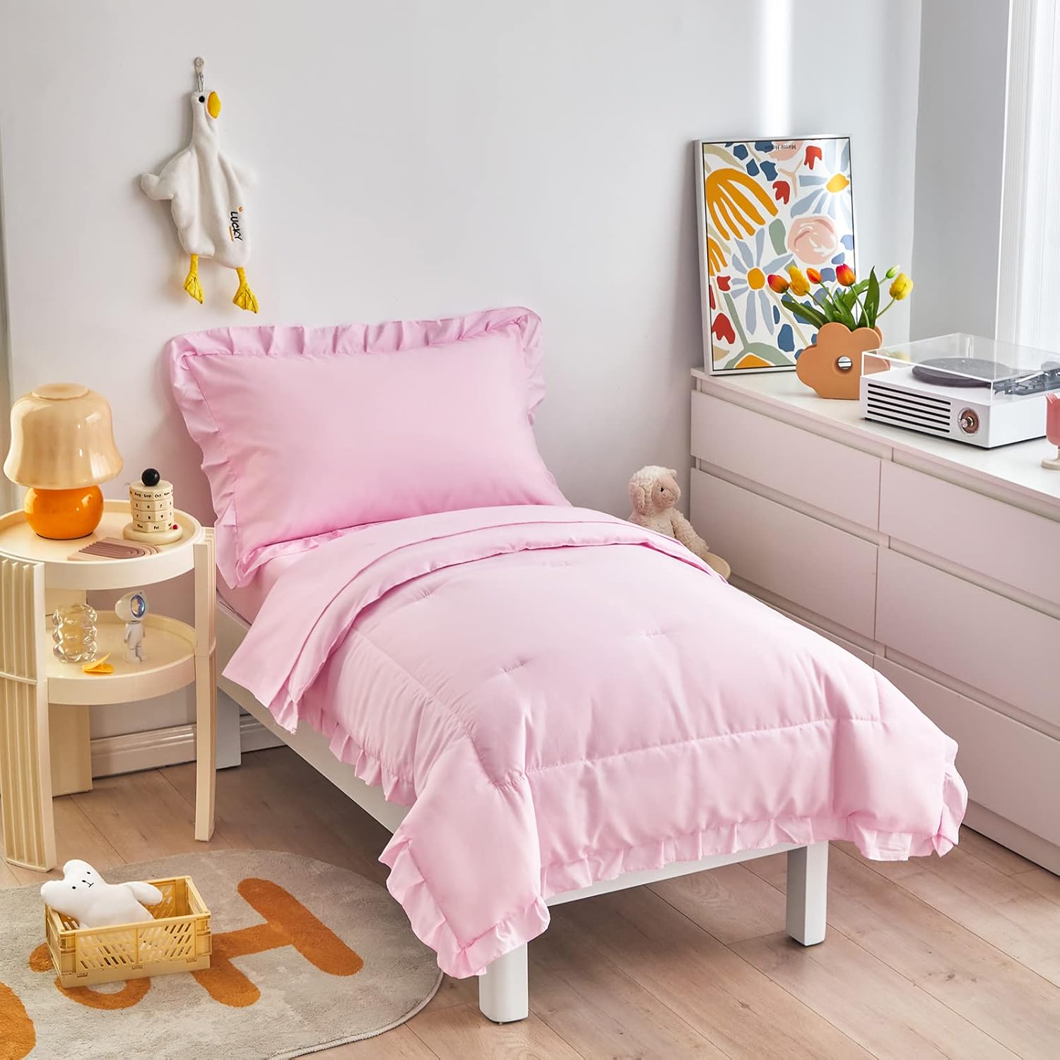 Uozzi Bedding four piece pink toddler bedding set showcasing the front view of the ruffled comforter on a bed.