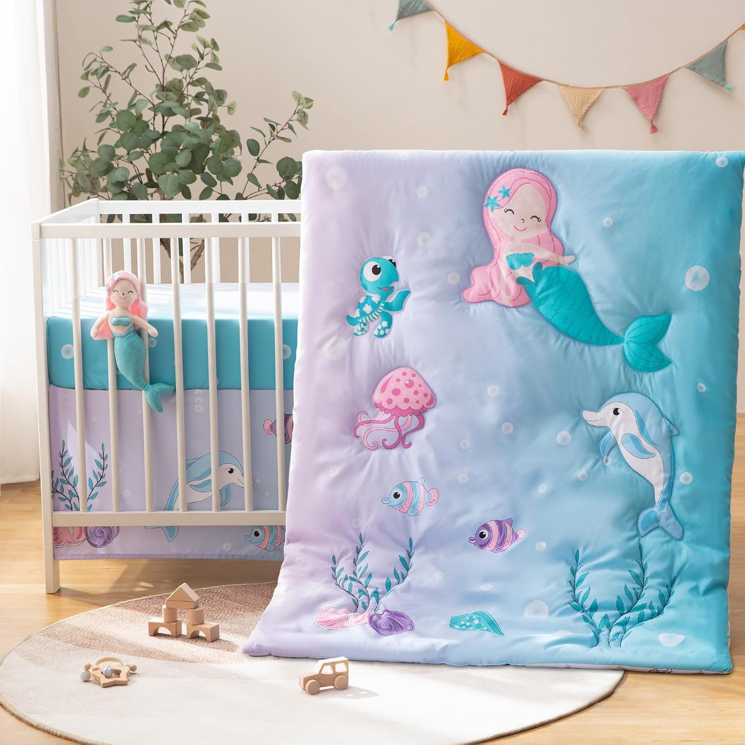 TCOYIWL 4 piece crib bedding set front view showcasing the reversible mermaid cartoon quilt and plush toy.