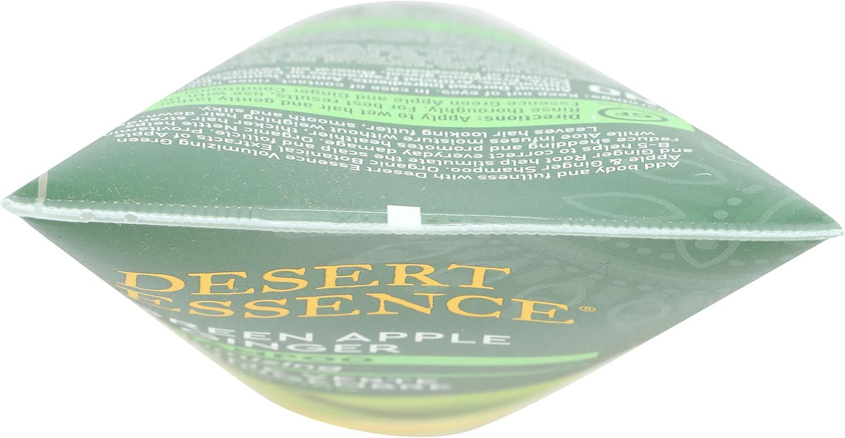 Desert Essence hair care bottle next to fresh green apple