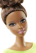 Close-up portrait of Barbie doll with brown hair and modern top.