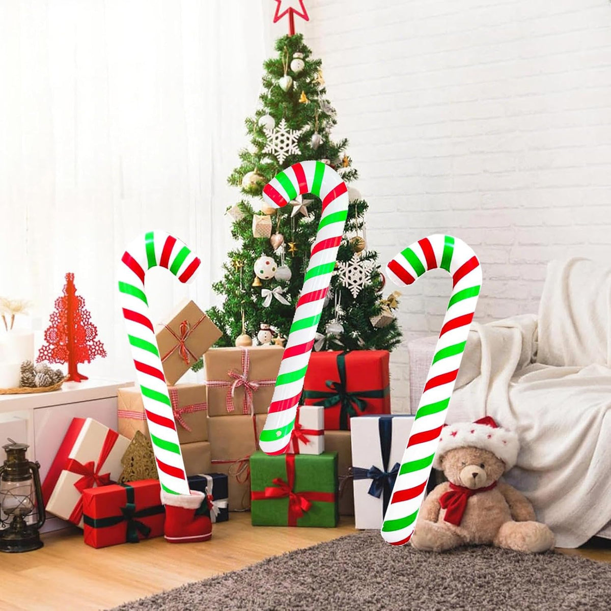Two pieces of large Soochat blow-up holiday balloons arranged next to a decorated Christmas tree.