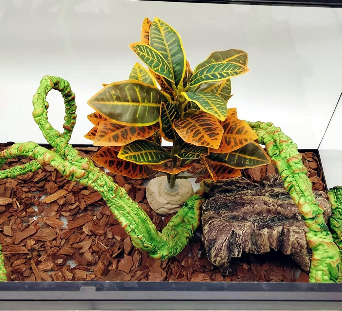 Side view of artificial reptile plant in a glass tank.