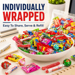 Hand holding a selection of individually wrapped fruit candies from the bulk bag