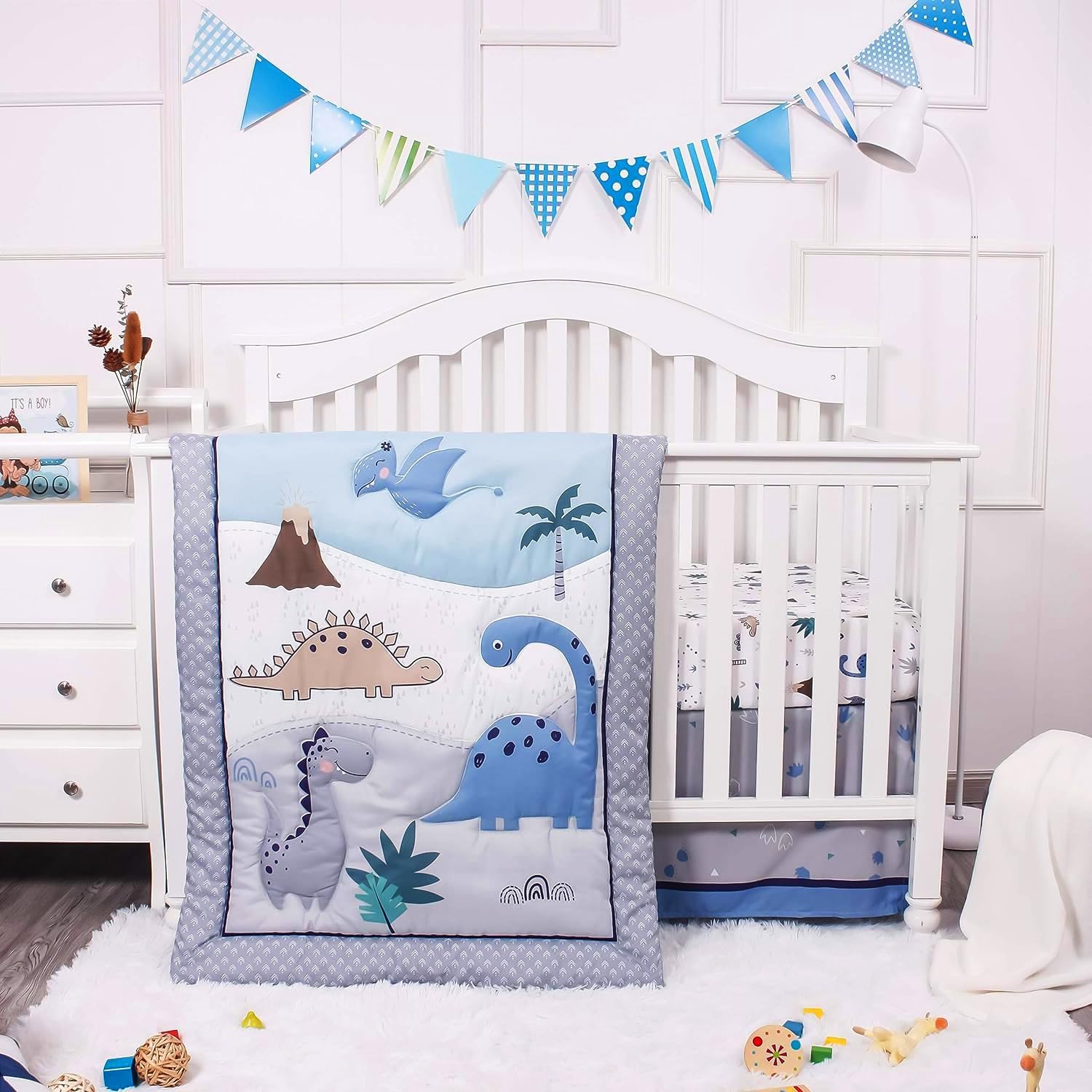 La Premura dinosaur baby crib bedding set front view showcasing the quilted comforter with blue and grey prehistoric landscape details.