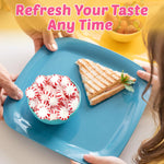 Individually wrapped red and white striped peppermint candy discs scattered on table