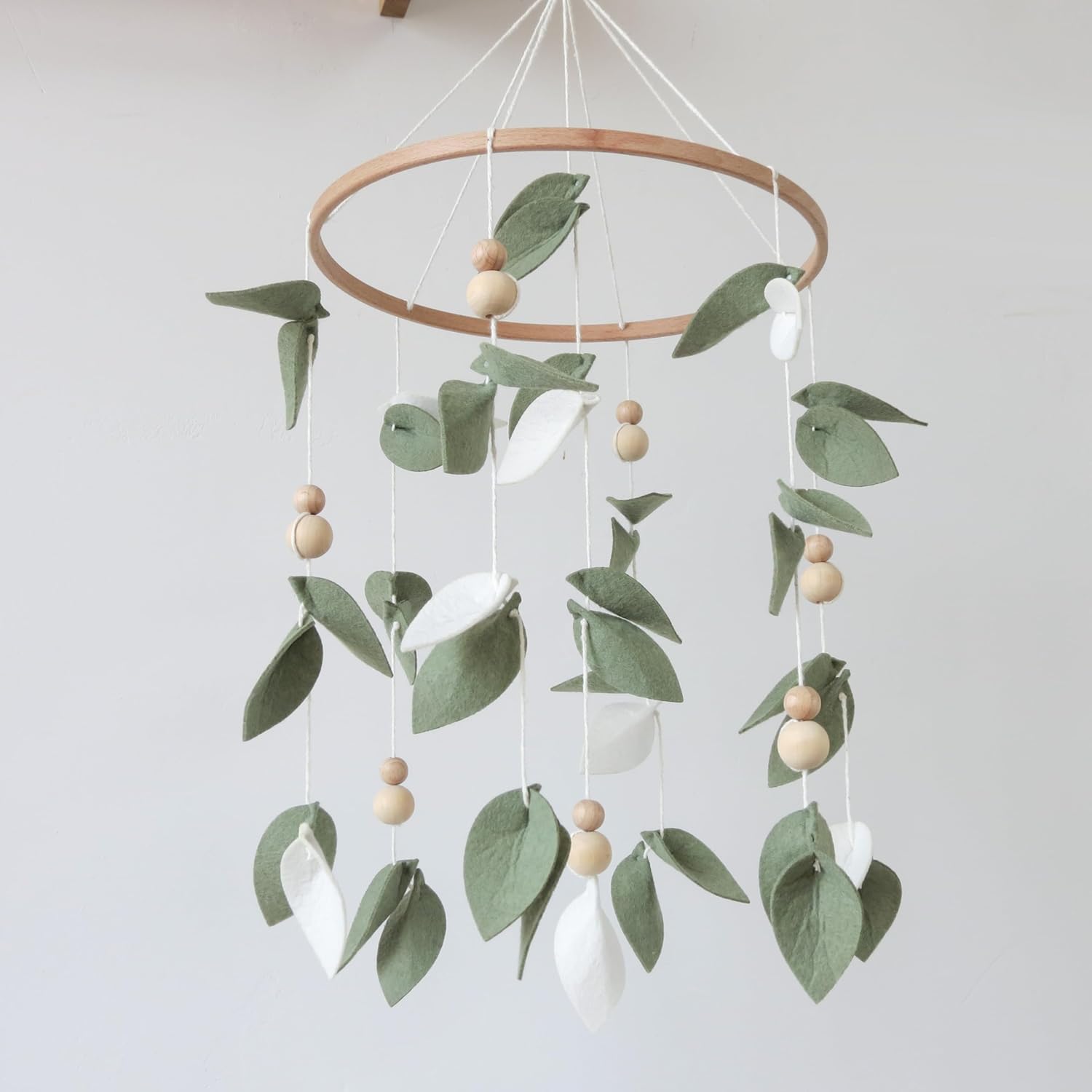 Goukurlsma Green Leaf Crib Mobile front view hanging over a wooden baby crib.