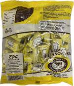 Individually wrapped Polish cream fudge candies scattered next to the original Krowki Milanowskie packaging.