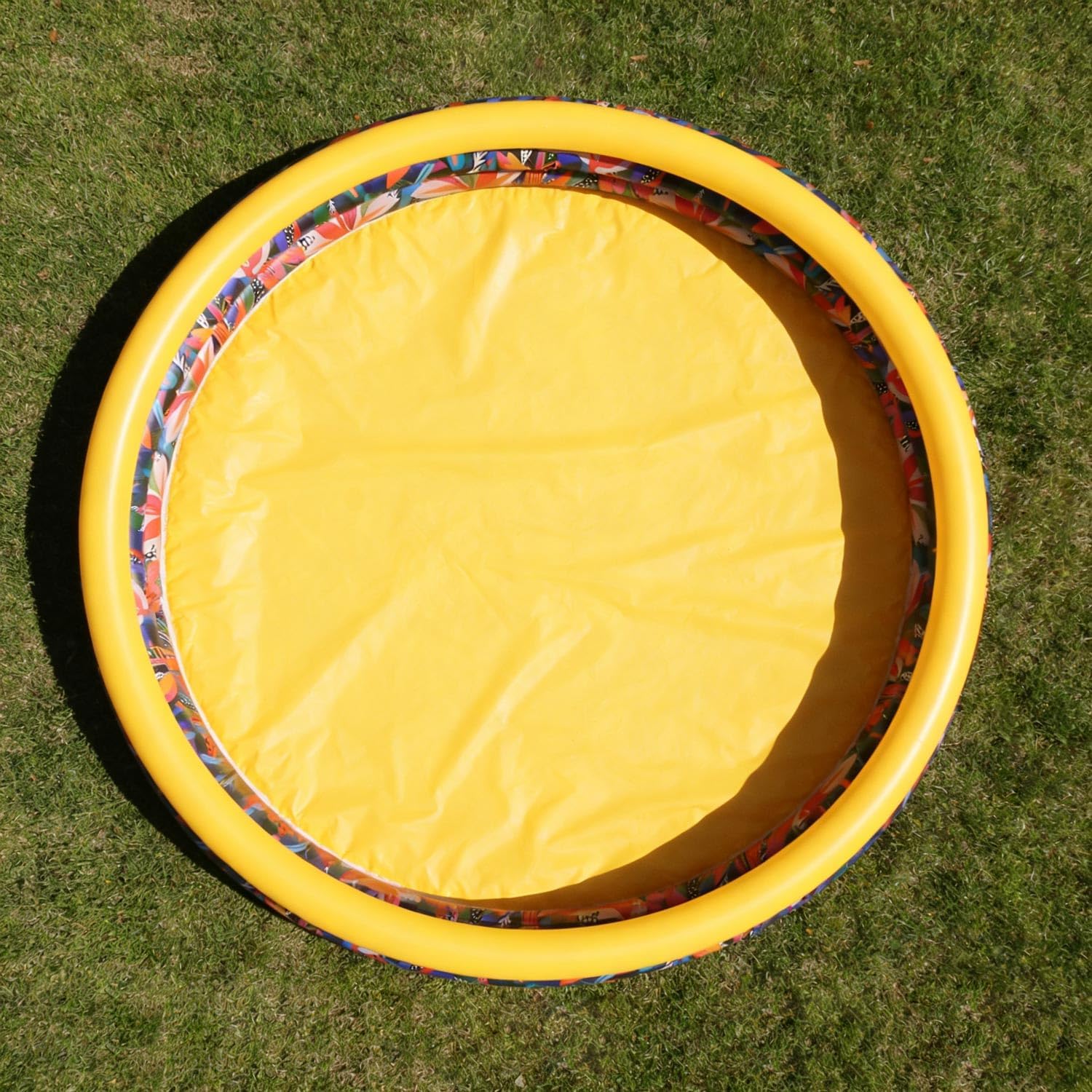 CHICLIST kids inflatable swimming pool front view showing the three jungle themed rings inflated in a backyard garden setting.