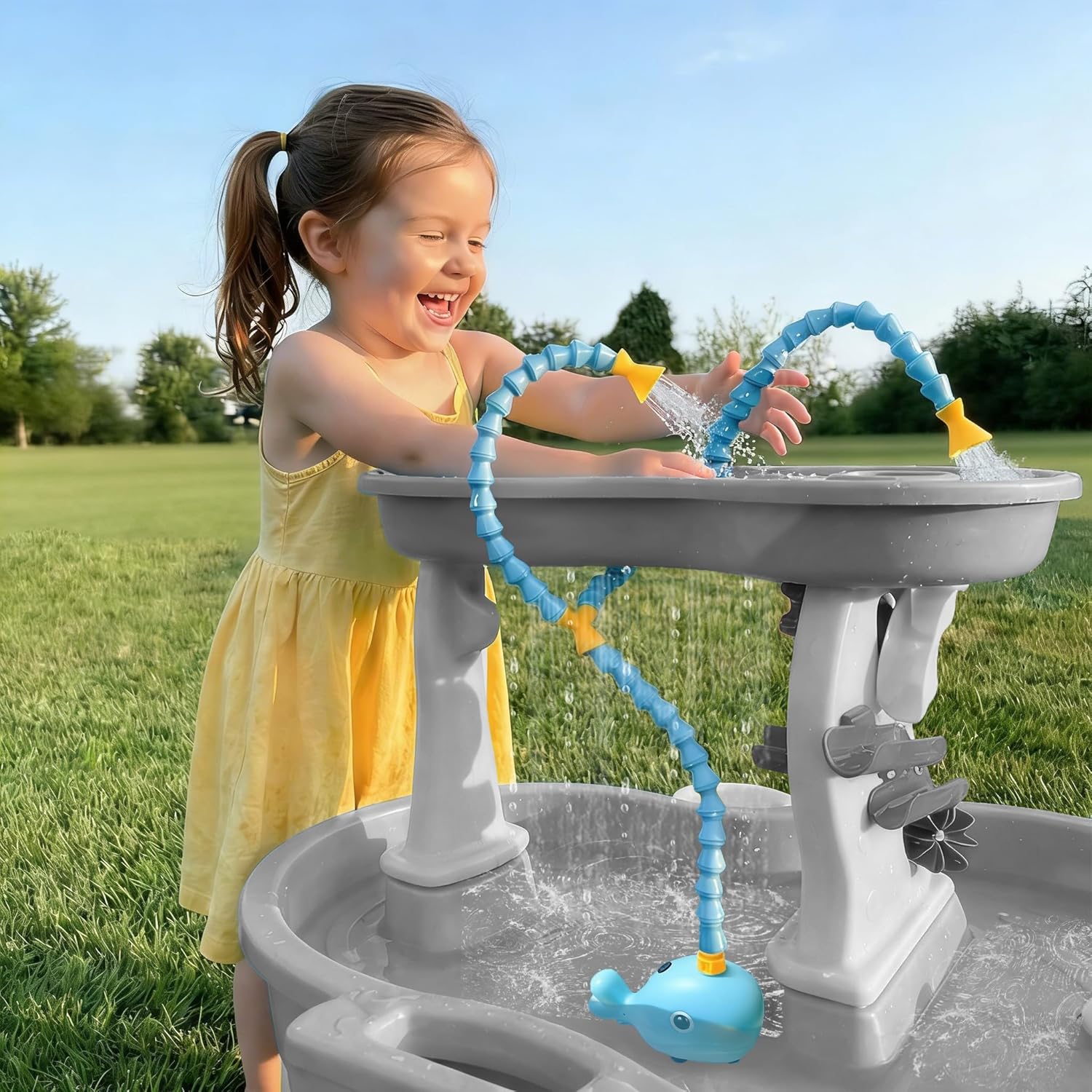 Aacabo Rechargeable Water Table Pump front view showing the blue whale design and flexible spouts in an outdoor play setup