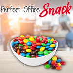 Close up view of colorful candy coated milk chocolate peanuts poured out of their packaging.