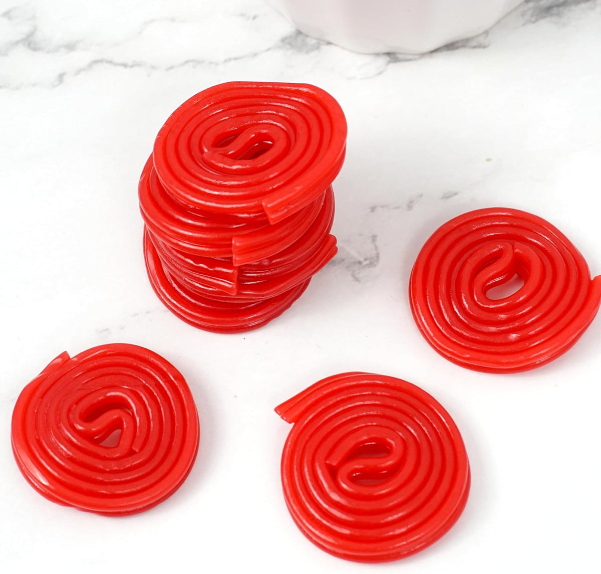 Chewy red licorice wheel candy being unrolled into a long string