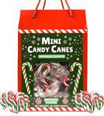 Mini peppermint candy sticks being used to garnish holiday hot cocoa.
