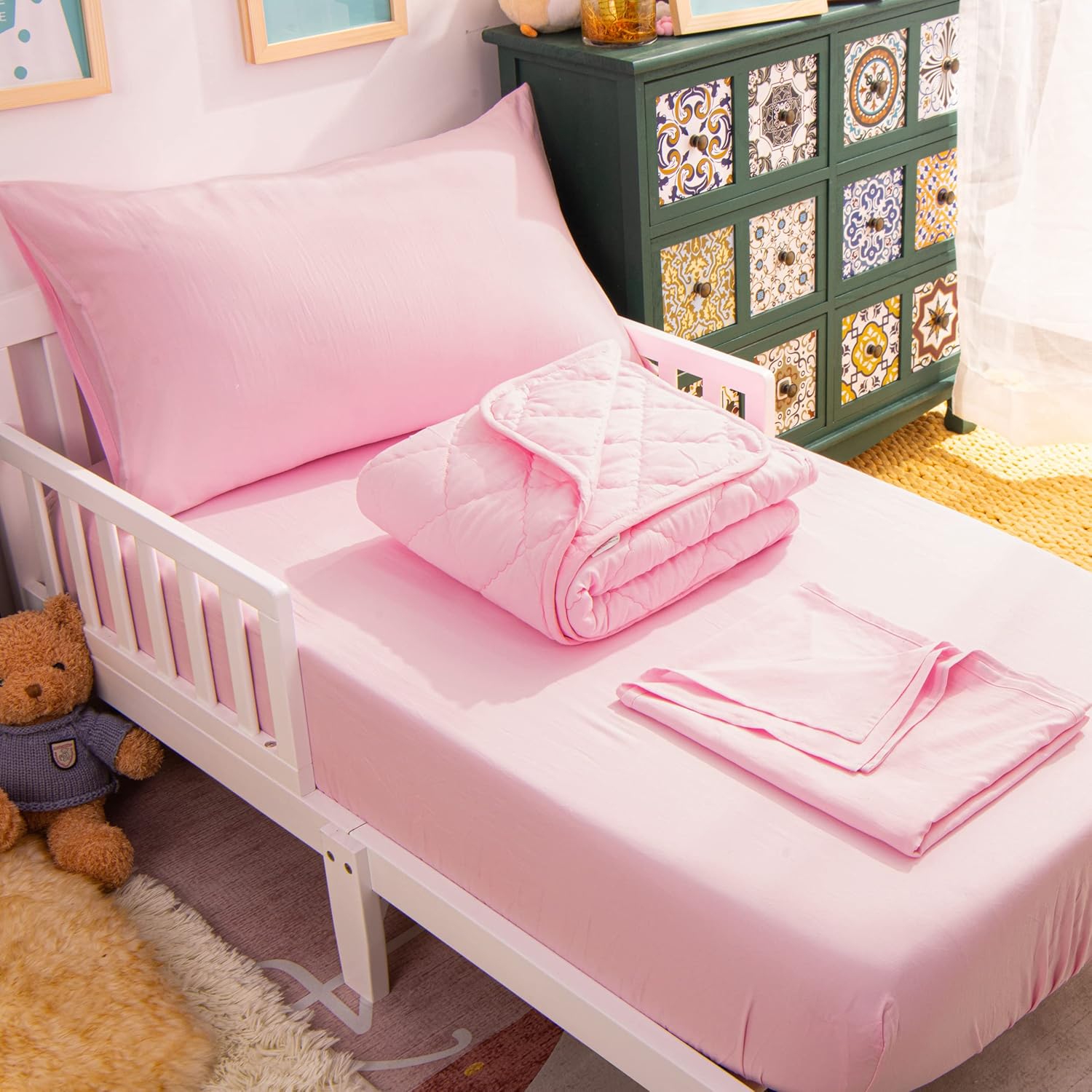 NTBAY toddler bedding set front view showcasing the soft pink quilted comforter and matching sheets inside a styled crib.