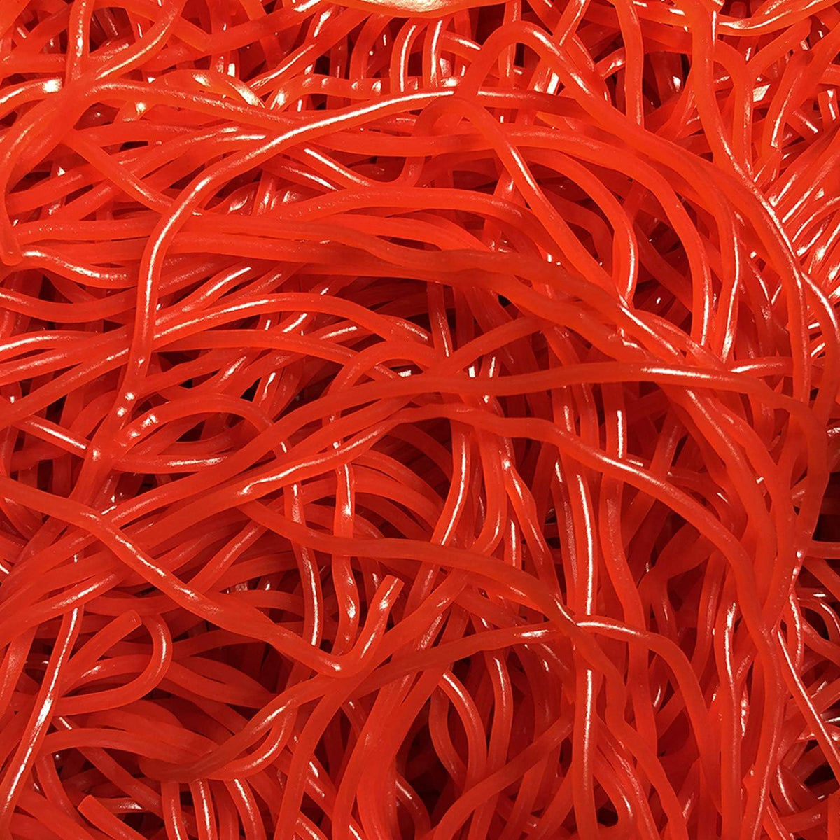 Long red candy straws showing detail of the chewy texture and vibrant strawberry color.