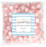 A pile of individual red and white swirled Starlight Peppermint hard candy pieces spread out on a table.