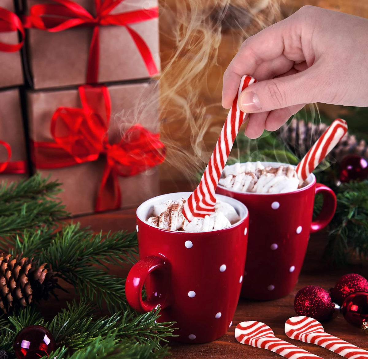 Red and white striped peppermint candy stirrer dipping into hot chocolate cup