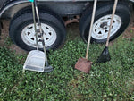Heavy duty one piece press molded metal rake clearing pet debris from backyard lawn grass.