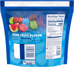 Assorted fruit shaped chewy candy pieces in green apple and blue raspberry flavors spread next to packaging