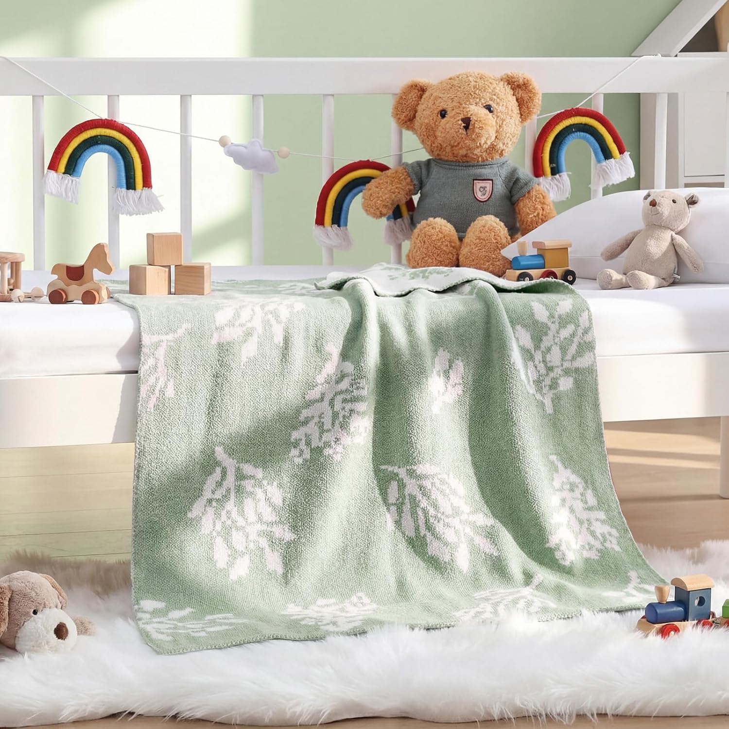 Hahafelt sage green chenille baby blanket front view draped over a modern white crib.