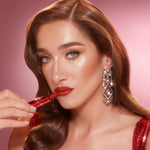 Charlotte Tilbury Fame Flame lipstick tube standing upright on a clean reflective surface highlighting the premium branding.