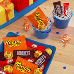 Close-up of individually wrapped Hershey's milk chocolate bars, Kit Kat wafers, and Reese's pieces.