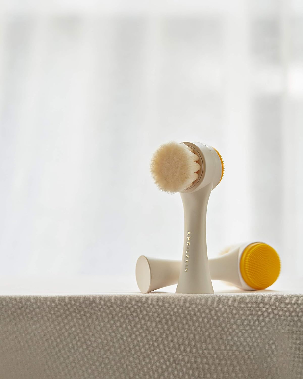 Ergonomic white handle of the Aprilskin dual cleansing pore brush held for skincare routine.