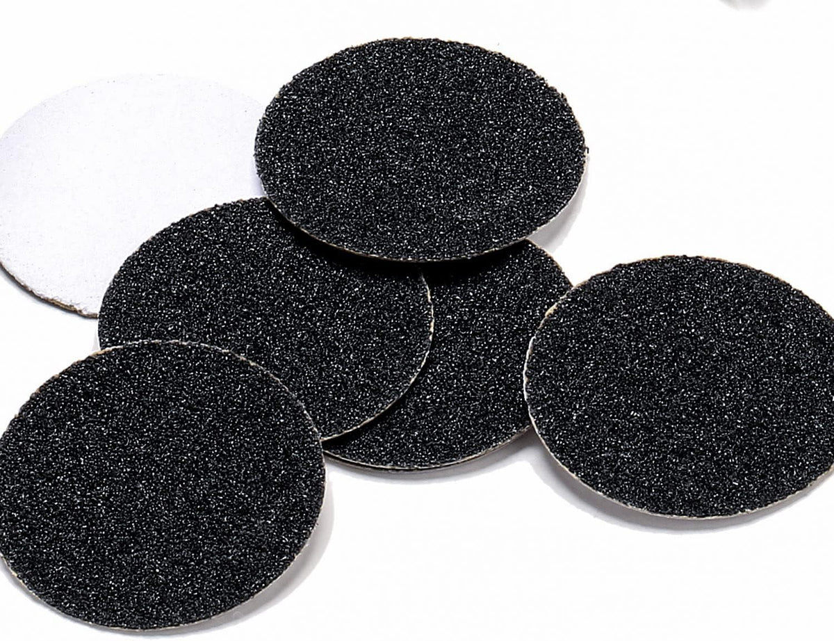 Self-adhesive black abrasive sandpaper discs stacked in storage container