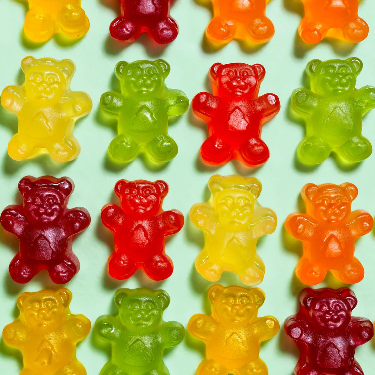 Six different flavors of Black Forest gummy bears lined up by color.