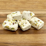 Individually wrapped pieces of pistachio divinity candy spilled from the packaging.
