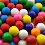 Assorted fruit flavored bubblegum balls pouring out of the twenty ounce packaging.