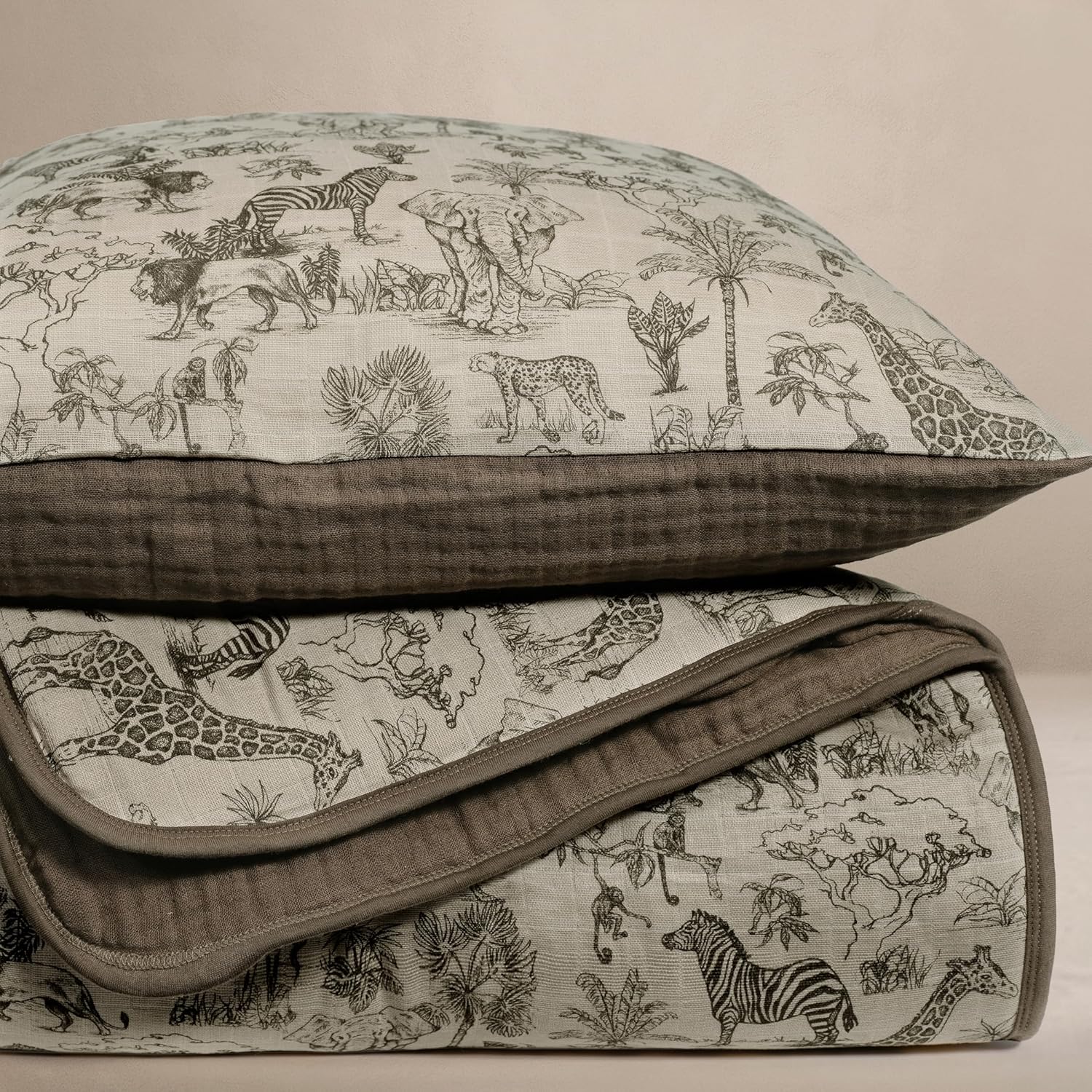 Oilo Vintage Safari organic cotton muslin crib quilt and sham set front view draped over a modern wooden nursery crib.