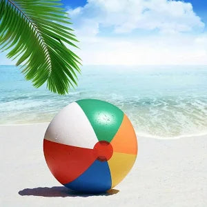 Colorful beach ball on a sandy beach with palm leaves and clear blue sky.