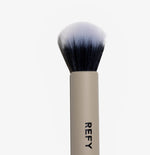 Close-up of the REFY dual-ended brush highlighting the white stippling bristles and dense buffing brush head