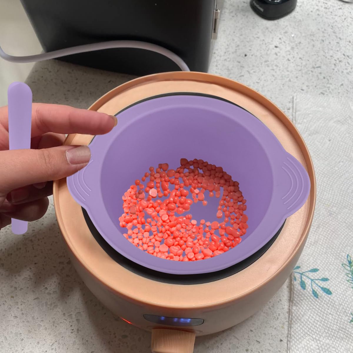 Flexible purple silicone wax warmer insert being squeezed to peel out hardened leftover wax